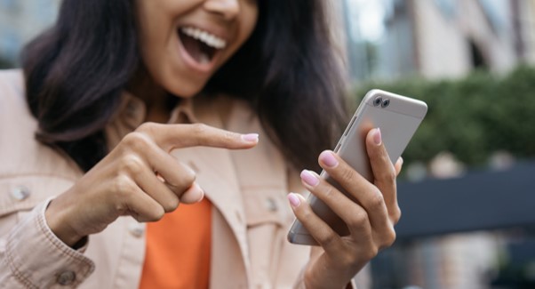 Photo d'une personne souriante qui pointe son doigt vers son écran de smartphone