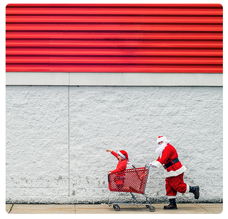 Photo d'un homme déguisé en père Noël tenant un caddie de courses