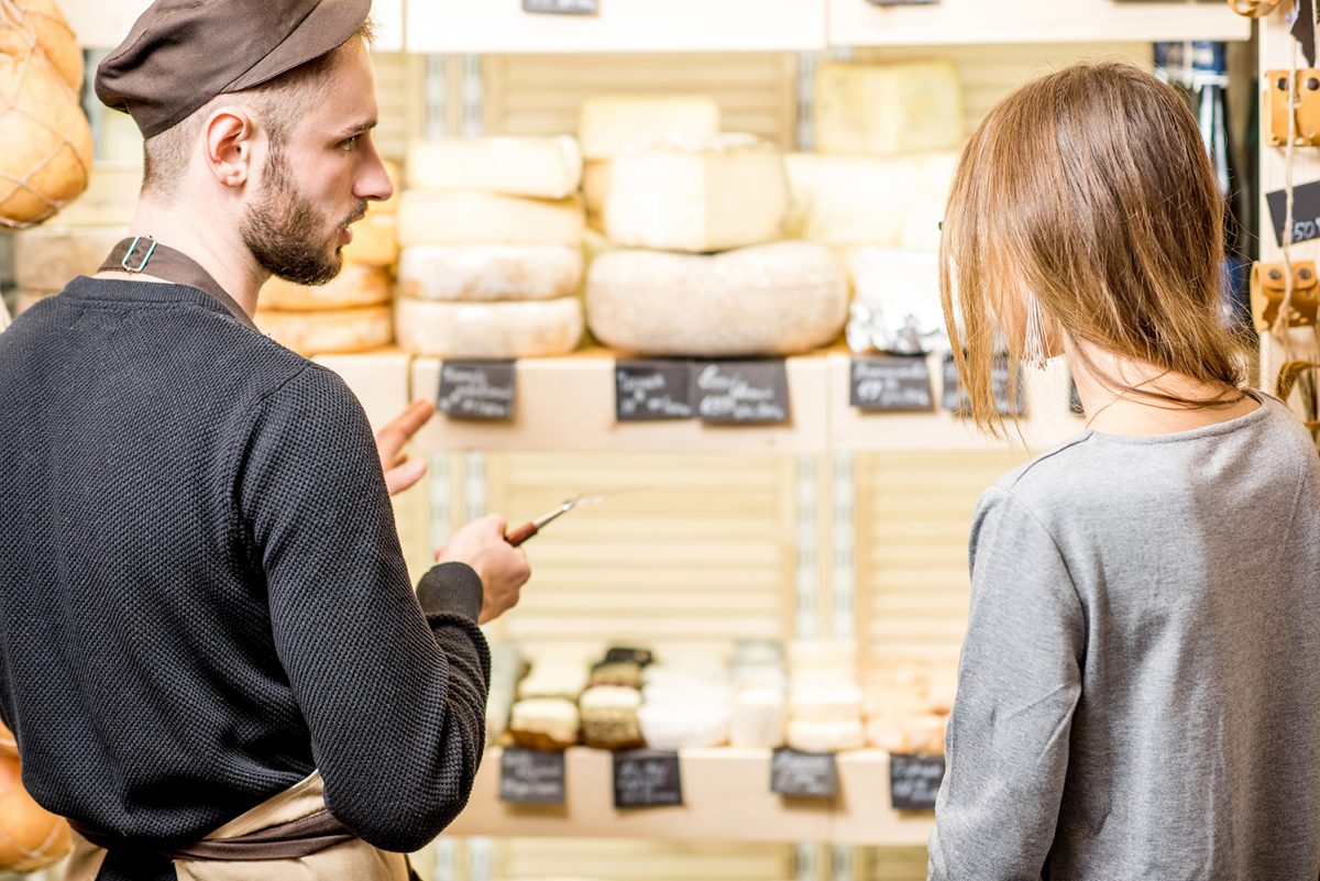 Photo représentant des producteurs locaux de fromage en magasin, vus de dos