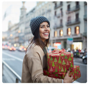 Photo d'une femme souriante avec les bras chargés de cadeaux